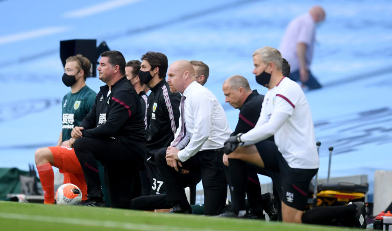 Burnley manager Sean Dyche and his staff take a knee before the Manchester City game
