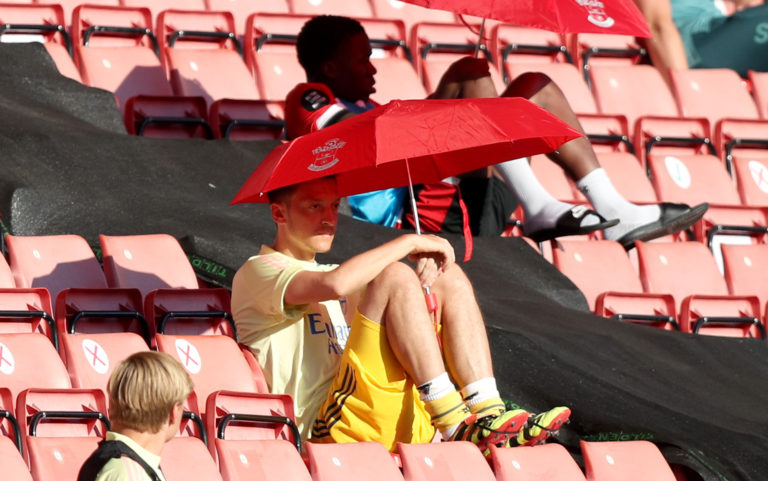 Arsenal's forgotten man Mesut Ozil shelters from the sun under a Southampton umbrella at St Mary's in June. Coronavirus restrictions resulted in substitutes being moved from dugouts and into the stands in order to comply with social distancing rules. Germany midfielder Ozil has not played a single minute of post-lockdown action going into the final day